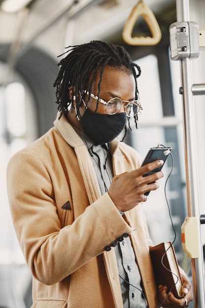 African American man riding in the city bus. Guy in a brown coat. Corona virus concept.