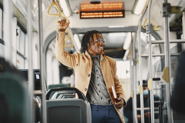 African American man riding in the city bus. Guy in a brown coat. Man with notebook.