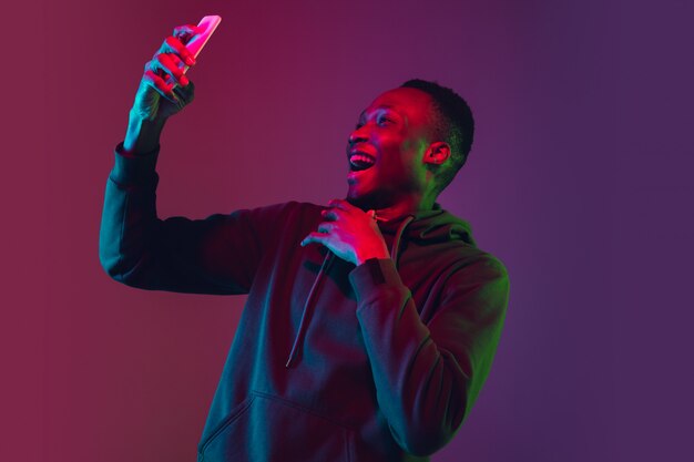 African-american man's portrait isolated on gradient wall in neon light