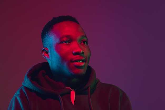 African-american man's portrait isolated on gradient wall in neon light