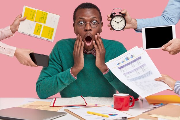 african american man sitting at desk surrounded with gadgets and papers