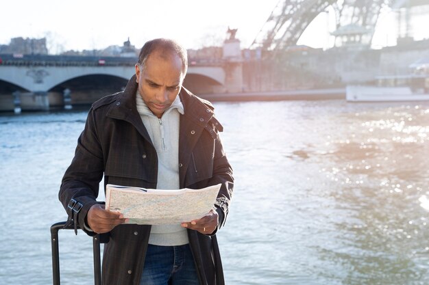 Афроамериканец смотрит на карту во время своего путешествия в париж