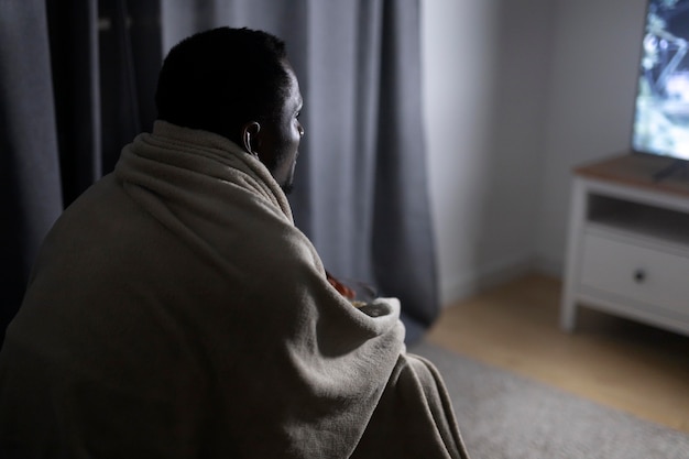 Free photo african american man watching streaming service at home alone