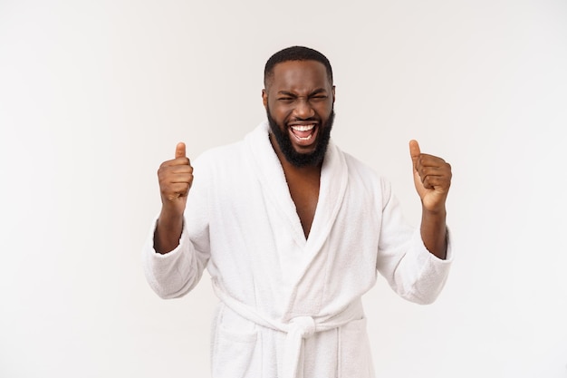 흰색 배경 위에 격리된 놀라움과 행복한 감정으로 목욕 가운을 입은 아프리카계 미국인 남자