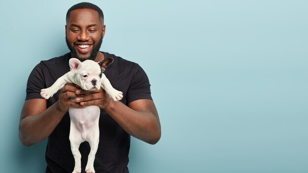 African American man wearing black T-shirt holding dog