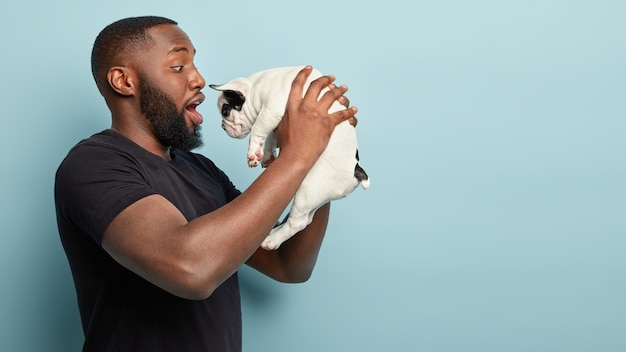 African American man wearing black T-shirt holding dog