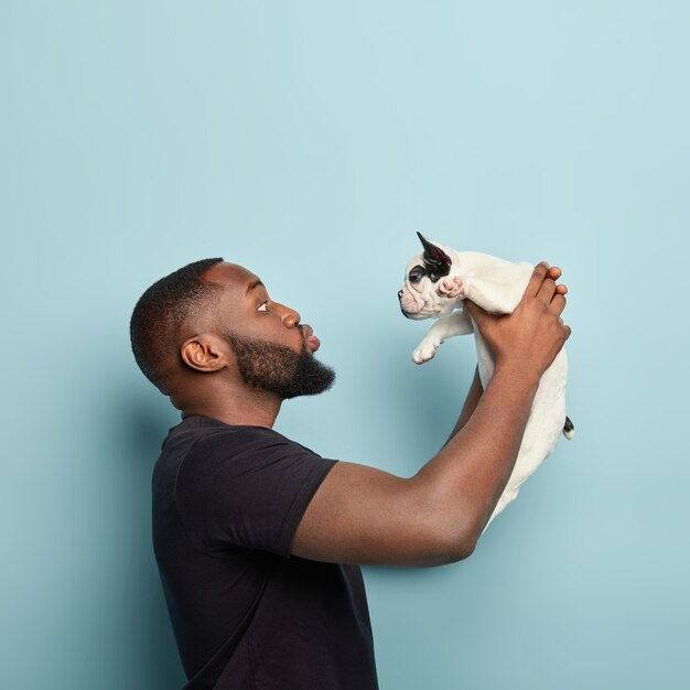 African American man wearing black T-shirt holding dog