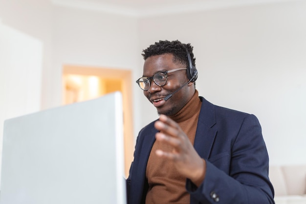 African American man wearing headphones reading good news in email getting new job promotion using laptop