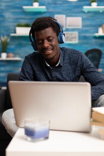 Free photo african american man wearing headphones using laptop