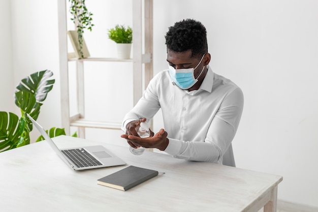 African american man wearing mask and cleaning his hands