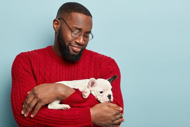 African American man wearing red sweater holding dog
