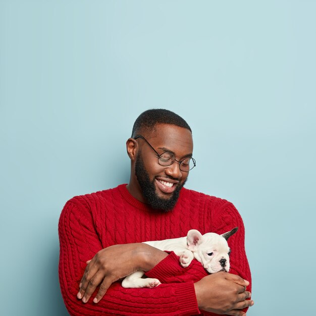 犬を保持している赤いセーターを着ているアフリカ系アメリカ人の男