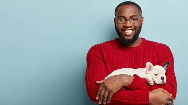 Афро-американский мужчина в красном свитере держит собаку