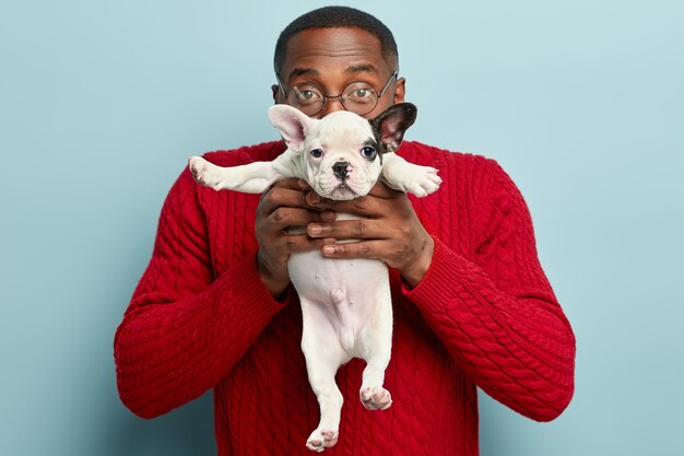 African American man wearing red sweater holding dog