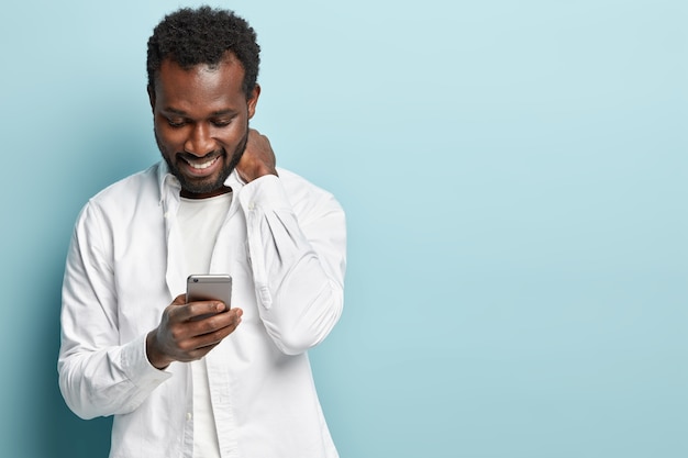 African American man wearing white shirt holding phone