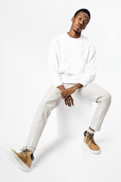 African American man in white sweater sitting on a chair full body