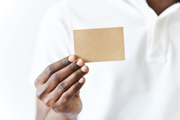 African American man in white T-shirt holding business card