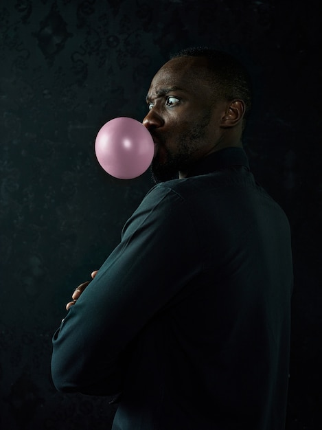 Free photo the african american man with bubble gum at studio over dark