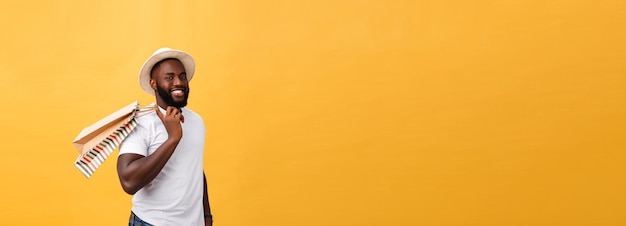 African american man with colorful paper bags isolated on yellow background