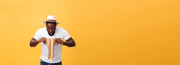 African american man with colorful paper bags isolated on yellow background