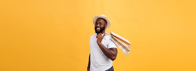 Uomo afroamericano con i sacchi di carta variopinti isolati su fondo giallo