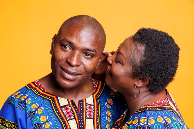 Free photo african american man and woman couple sharing secret, expressing love and affection. black woman whispering to husband ear, telling private romantic message on studio background