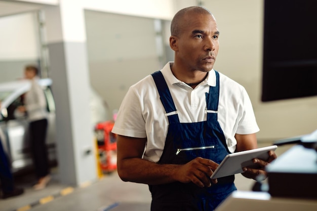 Free photo african american mechanic using touchpad while working on a computer at repair shop