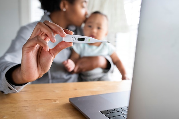 African American mom showing baby&rsquo;s fever to doctor through telemedicine call