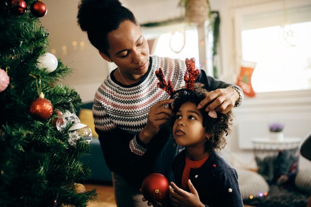 Афроамериканская мать и дочь готовятся к Рождеству дома