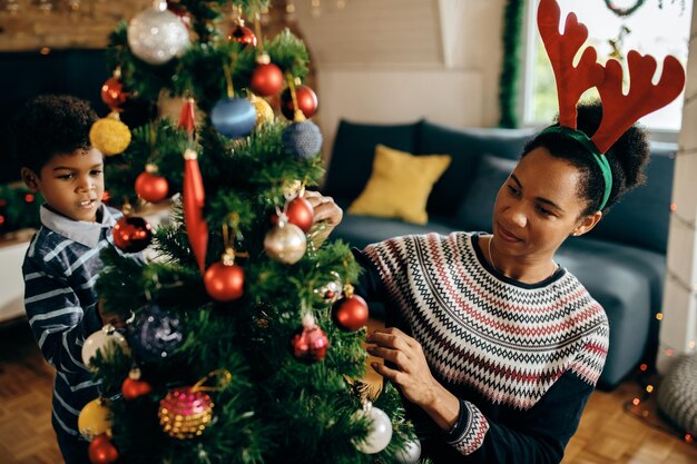 家でクリスマスツリーを飾るアフリカ系アメリカ人の母と息子