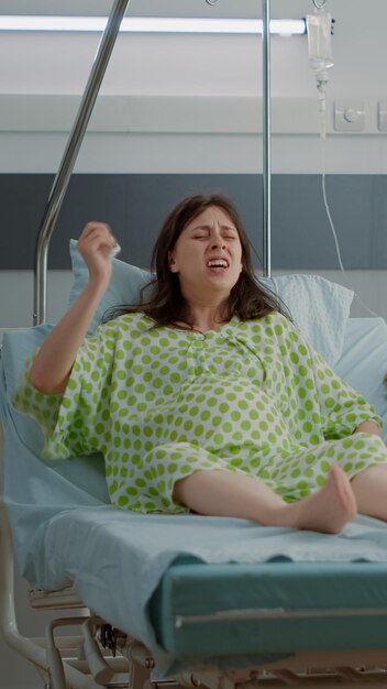 African american nurse assisting pregnant patient with painful labor laying in hospital ward bed. Caucasian woman with pregnancy preparing for childbirth at maternity with husband