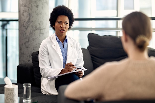 Free photo african american psychologist talking to a patient during an appointment at her office