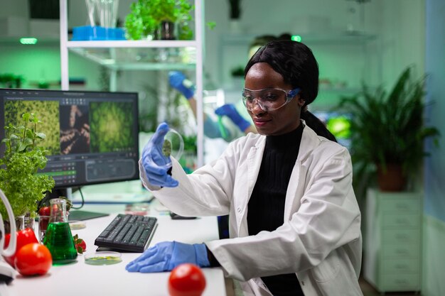 African american scientist holding petri dish with green leaf sample