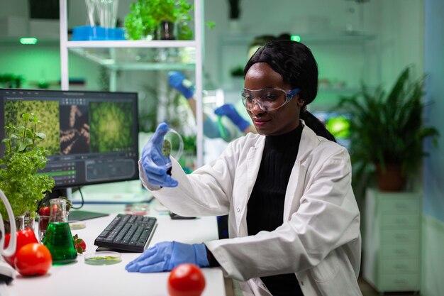 녹색 잎 샘플이 있는 페트리 접시를 들고 있는 아프리카계 미국인 과학자