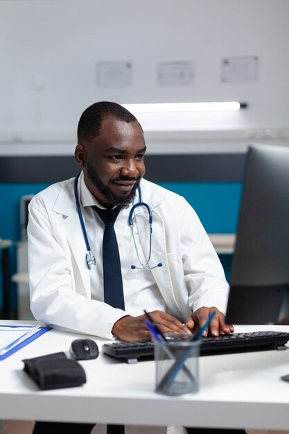 African american specialist physician analyzing sickness expertise on computer