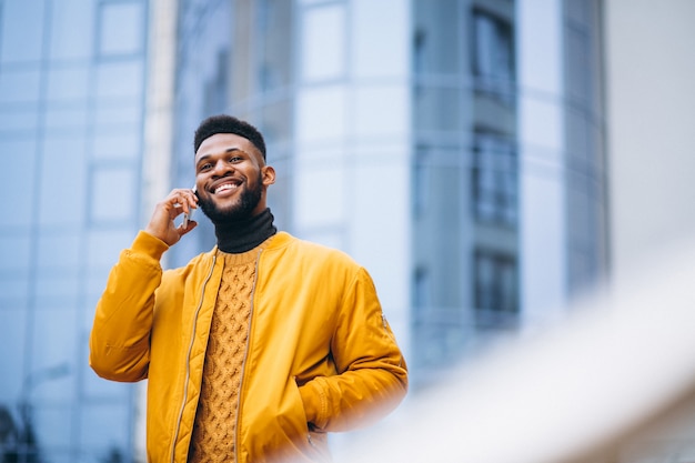 Афро-американский студент идет по улице и разговаривает по телефону