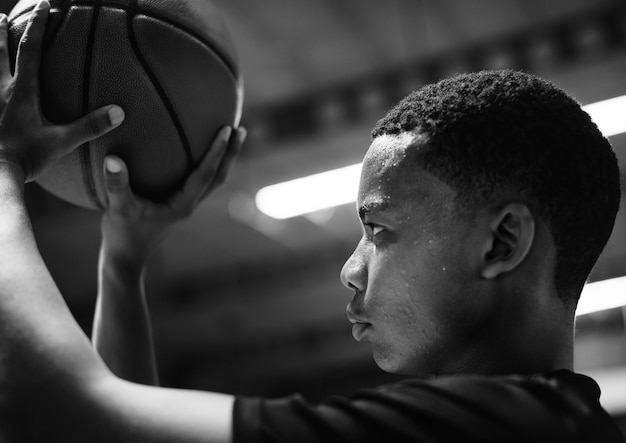 African American teenage boy concentrated on playing basketball