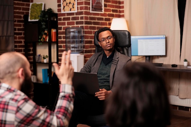 African american therapist listening to people at couple therapy session, doing psychoanalysis on laptop. Psychology specialist helping with relationship issues and conflict.