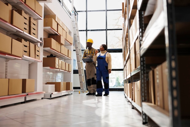 Free photo african american warehouse distribution manager doing inventory with assistant