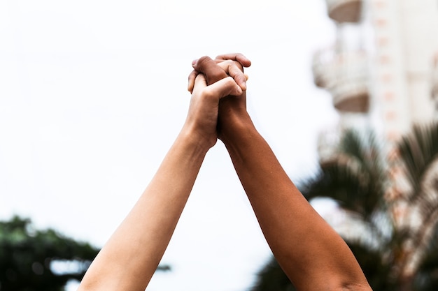 Free photo african-american and white people holding hands extended upwards