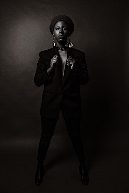 African-American woman in a black suit with big earrings posing