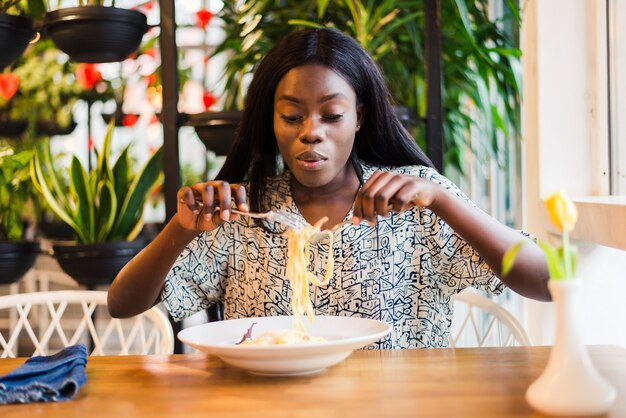 African american woman in cafe eat spaghetti pasta