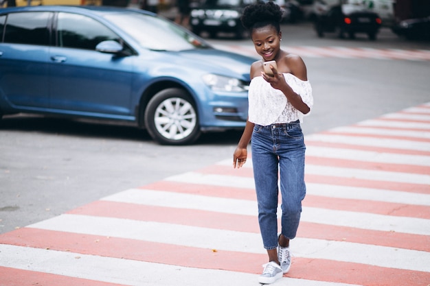 Strada dell'incrocio della donna dell'afroamericano con il telefono