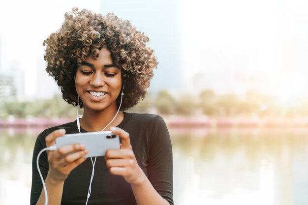 African American woman holding smartphone in the nature remixed media