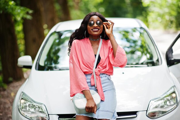 African american woman posed against white car in forest road