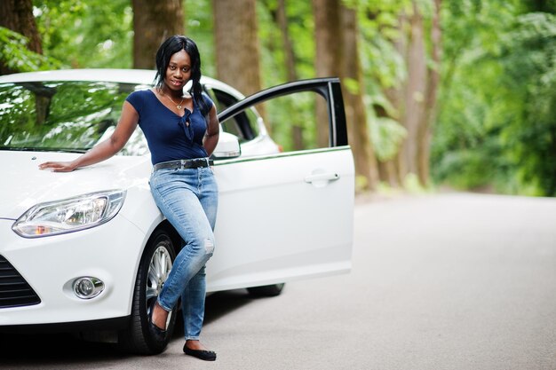 African american woman posed against white car in forest road