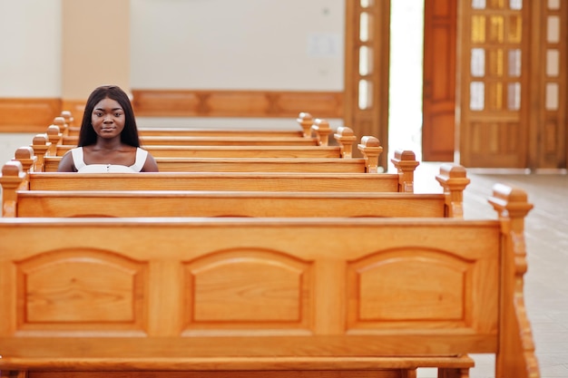 Афроамериканка молится в церкви Верующие медитируют в соборе и во время духовной молитвы Афро девушка сидит на скамейке