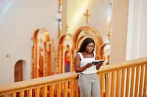 Free photo african american woman praying in the church believers meditates in the cathedral and spiritual time of prayer afro girl with holy bible at hands