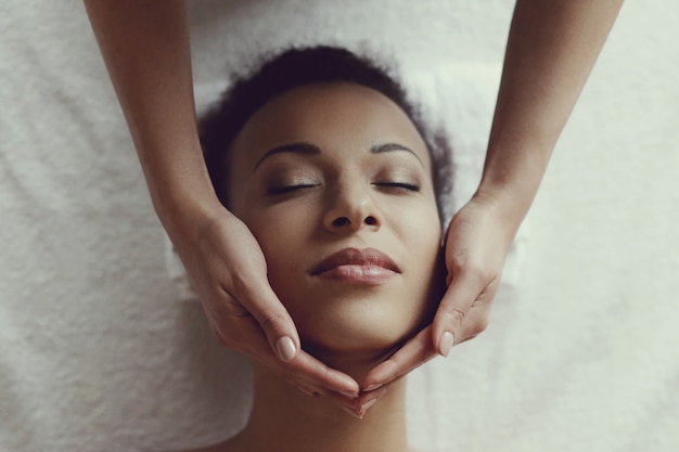 Афро-американская женщина получает расслабляющий массаж в спа-салоне