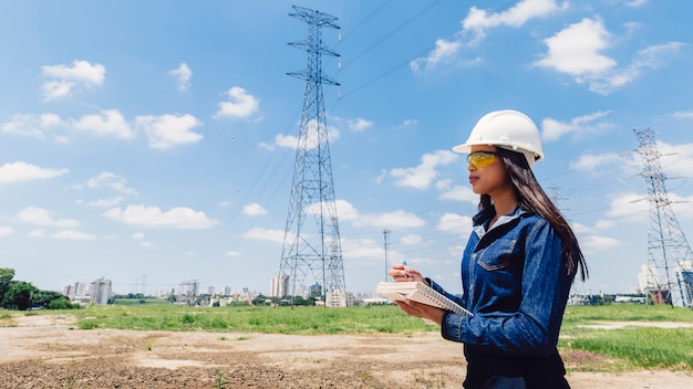 Free photo african american woman in safety helmet taking notes near high voltage line